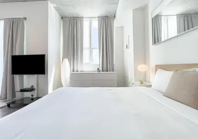 a white bedroom with a large bed and a television at Center Stage- Downtown Parking Pool Hot Tub in Miami