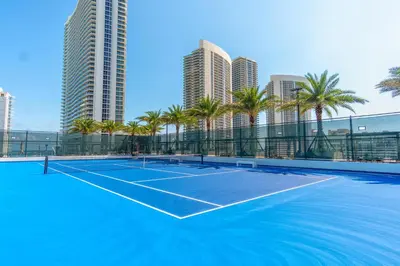 a tennis court with palm trees and buildings at Hyde Beach House 2601 in Hollywood
