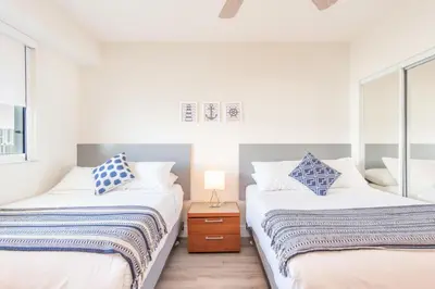 two beds in a room with white walls and windows at Marina Bay 1008 in Miami Beach