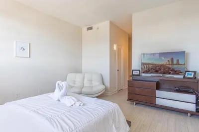 a bedroom with a white bed with a dresser and a chair at Ocean Reserve PH6 in Miami Beach
