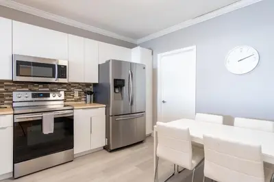 a kitchen with white cabinets and a stainless steel refrigerator at Golden Bay 808 in Miami Beach