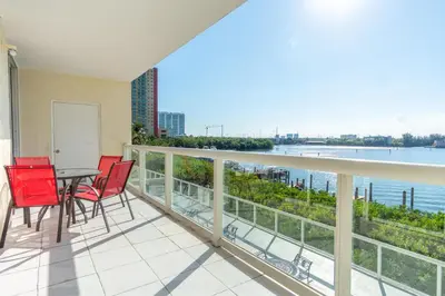 a balcony with a table and chairs and a view of the water at Golden Bay 406 in Miami Beach