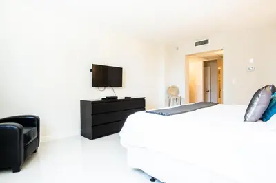 a white bedroom with a bed and a tv at Ocean Reserve 927 in Miami Beach