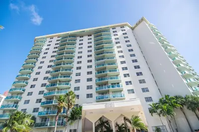 a tall white building with palm trees in front of it at Ocean Reserve 1112 in Miami Beach