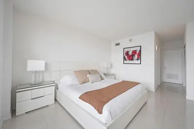 a white bedroom with a large bed and a lamp at Ocean Reserve 1616 in Miami Beach