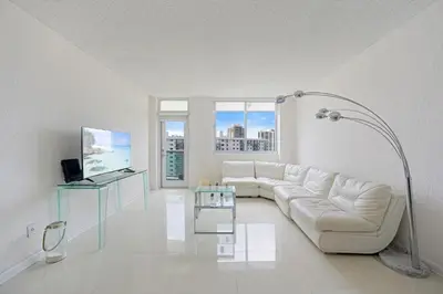 a white living room with a white couch and a lamp at Ocean Reserve 1616 in Miami Beach