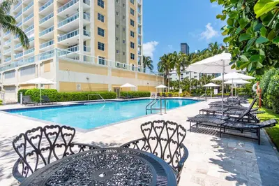 a pool with chairs and a table and a building at Golden Bay 508 in Miami Beach