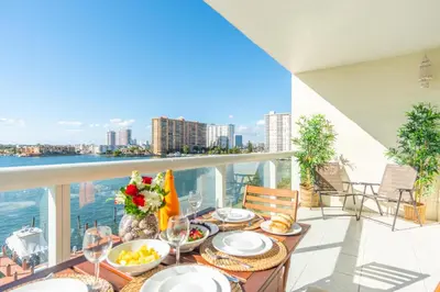 a table on a balcony with a view of the water at Golden Bay 606 in Miami Beach