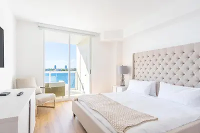 a white bedroom with a large bed and a window at Golden Bay 502 in Miami Beach