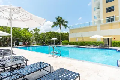 a swimming pool with chairs and umbrellas next to a building at Golden Bay 302 in Miami Beach