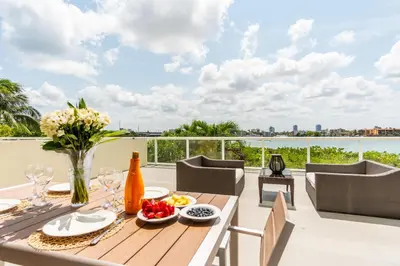 a dining table on a balcony with a view of the water at Golden Bay 303 in Miami Beach