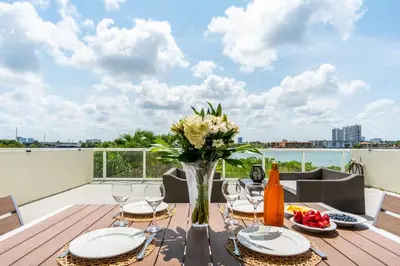 a dining table with a vase of flowers on a balcony at Golden Bay 303 in Miami Beach