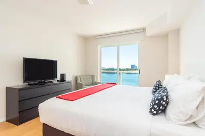 a white bedroom with a large bed and a tv at Golden Bay 707 in Miami Beach