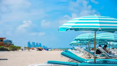 a group of chairs and umbrellas on a beach at 1 Bedroom Private Residence at Carillon Miami Resort -911 in Miami Beach