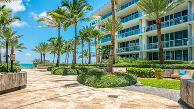 a building at the beach with palm trees at 1 Bedroom Private Residence at Carillon Miami Resort -911 in Miami Beach