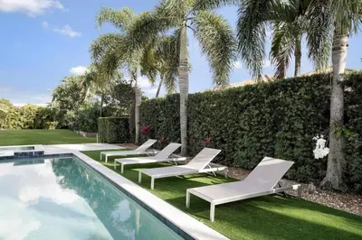 a pool with chaise lounge chairs and palm trees at Luxury home w pool by PMI in Miami
