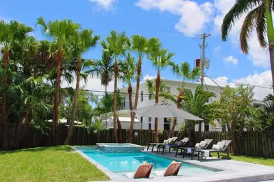 a pool with chairs and an umbrella and palm trees at Fox Private Resort-Heated Pool, Spa-Downtown&Beach in Fort Lauderdale