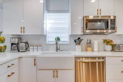 a white kitchen with a sink and a microwave at Fox Garden-Heated Pool-Spa- Boho-Downtown & Beach in Fort Lauderdale
