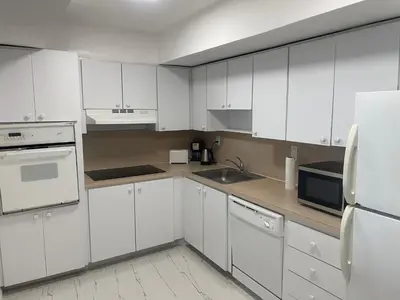 a kitchen with white cabinets and a sink and a refrigerator at Beautiful Apartment in Sunny Isles STR-01432 in Miami Beach