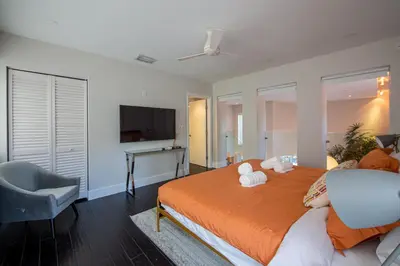 a bedroom with a bed with a chair and a television at Fascinating Luxe Two-Level Villa BY THE GLAMHOMES in Biscayne Park
