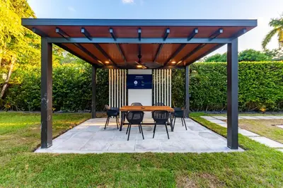a wooden pavilion with a table and chairs in the grass at Fascinating Luxe Two-Level Villa BY THE GLAMHOMES in Biscayne Park