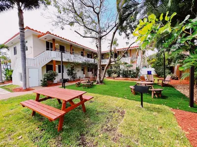 a picnic table in front of a building with a grill at The Leeward Apartments By Lowkl in Fort Lauderdale