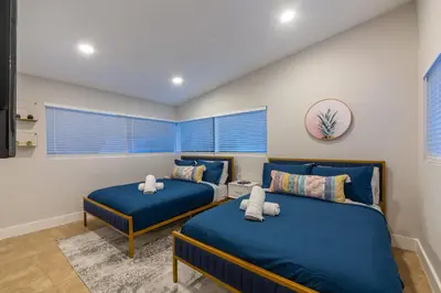 two beds in a room with blue sheets at Super Fun Villa Game Room BY THE GLAMHOMES in North Miami Beach