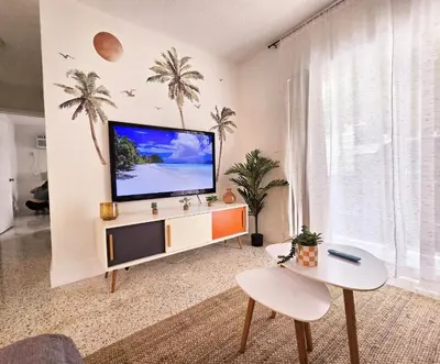 a living room with a flat screen tv and palm trees at Cozy Apartment Near Brickell in Miami