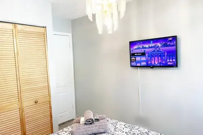 a bedroom with a tv on the wall and a bed at Amazing & cozy Duplex near Zoo Miami ! in Miami