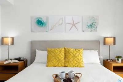 a bedroom with a white bed with two tables and two lamps at Apartment w Balcony Gym Near Beach in Hallandale Beach