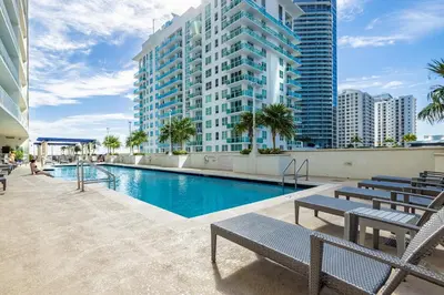 a swimming pool with benches and a building at Brickell Apt with Bay Views, Pool, Free Parking in Miami