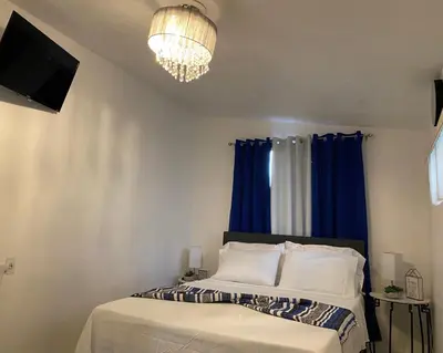 a bedroom with a bed with blue curtains and a tv at Beautiful House 7 min from Miami Airport w FREE parking in Miami