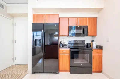 a kitchen with black appliances and wooden cabinets at TRUMP INTERNATIONAL BEACH RESORT 2 BEDROOM APARTMENT 1600 Sf Ocean and Bay View in Miami Beach