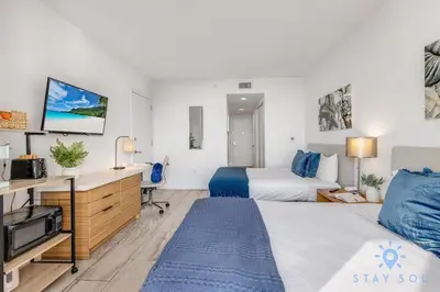a hotel room with a bed and a desk and a tv at Upper studio Balcony Pool Gym - Near Beach in Hallandale Beach