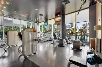a gym with cardio equipment in a building with windows at Infinite View with Balcony and Resort, Pool, Gym in Hallandale Beach
