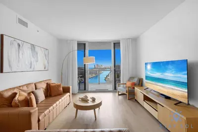 a living room with a couch and a large screen tv at MODERNResortBALCONY in Hallandale Beach