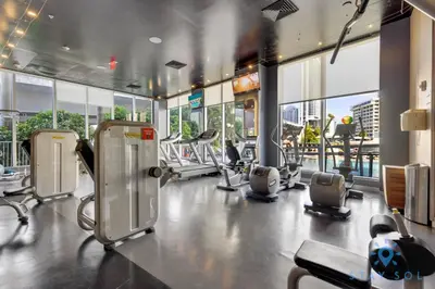a gym with cardio equipment in a building with windows at MODERNResortBALCONY in Hallandale Beach