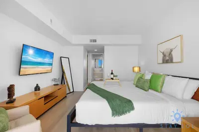 a bedroom with a large white bed with green pillows at Infinite View Balcony Pool in Hallandale Beach