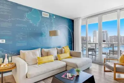 a living room with a white couch and a blue wall at Pool - Apartment with Balcony - Gym - Near Beach in Hallandale Beach