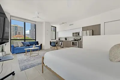 a white bedroom with a large bed and a kitchen at Devereaux Miami Luxury One-Bedroom and Studios in Miami