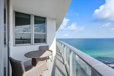 a balcony with a table and chairs and the ocean at Ocean Views Perfect Location Resort Amenities in Hallandale Beach