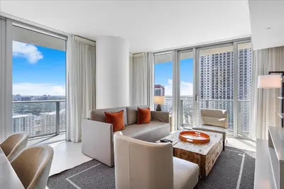 a living room with a couch and a table and windows at Ocean Views Perfect Location Resort Amenities in Hallandale Beach