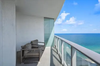 a balcony with a chair and the ocean at Ocean Views Perfect Location Resort Amenities in Hallandale Beach