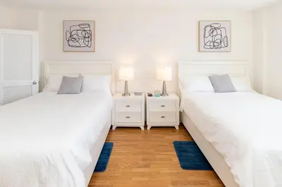 two white beds in a room with two lamps at Modern Oceanview Condo - Steps to the Beach! in Miami Beach