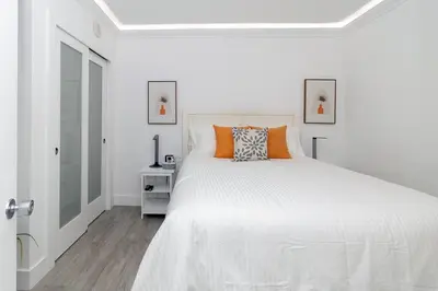 a white bedroom with a large white bed with orange pillows at Stunning & Spacious Resort-Style Condo Across From Beach! in Miami Beach