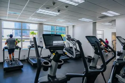 a gym with cardio machines and a man standing in front of a window at Brickell, Miami Home in the Sky! in Miami