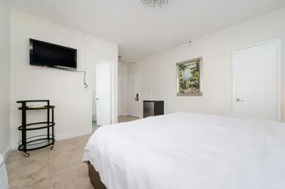 a white bedroom with a bed and a flat screen tv at Starlite Hotel in Miami Beach