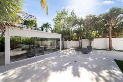 an outdoor patio with a white canopy and palm trees at Deco Boutique Hotel in Fort Lauderdale