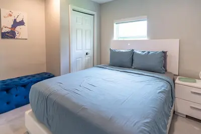 a bedroom with a bed with blue sheets and a window at Hollywood Paradise Luxury 4BR 3BA Home and Outdoor Fun with Heated Pool in Hollywood