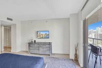 a bedroom with a bed and a dresser and a window at Luxury condo with ocean view 4Bedrooms 3Bathrooms in Hallandale Beach